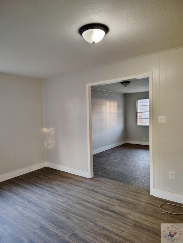 empty room featuring a textured ceiling and dark hardwood / wood-style flooring