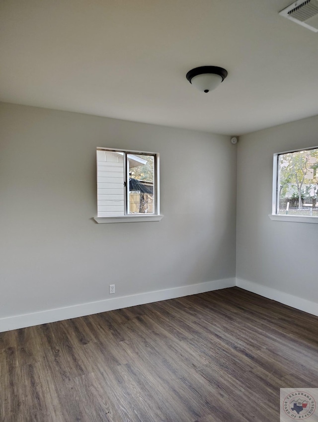 spare room with dark wood-type flooring and a healthy amount of sunlight