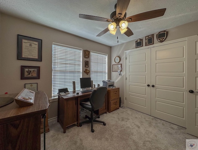 office area featuring light carpet, ceiling fan, and a textured ceiling