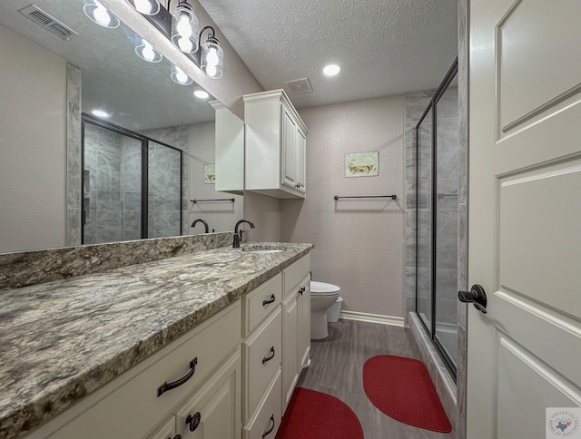 bathroom with vanity, toilet, a textured ceiling, and walk in shower