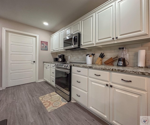 kitchen with backsplash, appliances with stainless steel finishes, and white cabinets