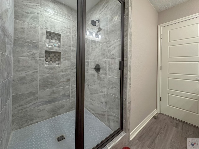 bathroom featuring hardwood / wood-style flooring, an enclosed shower, and a textured ceiling