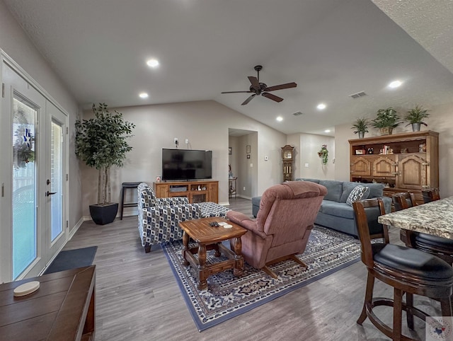 living room with lofted ceiling, ceiling fan, and light hardwood / wood-style flooring