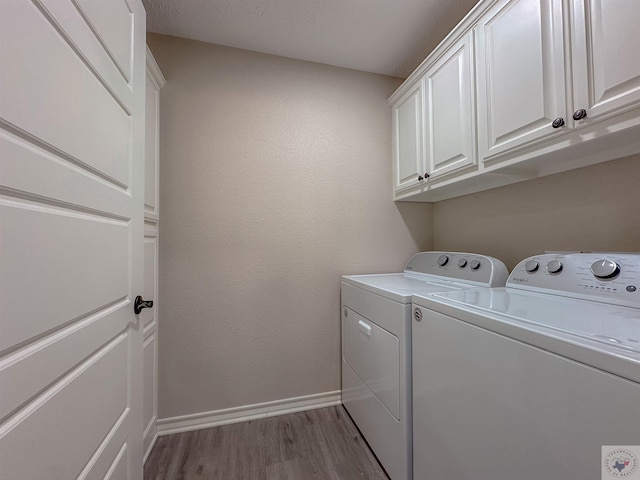 clothes washing area featuring cabinets, wood-type flooring, and washer and dryer