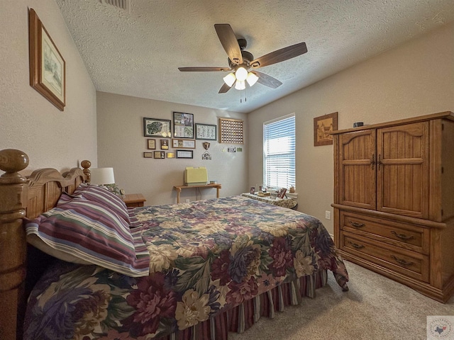 bedroom with a textured ceiling, light colored carpet, and ceiling fan