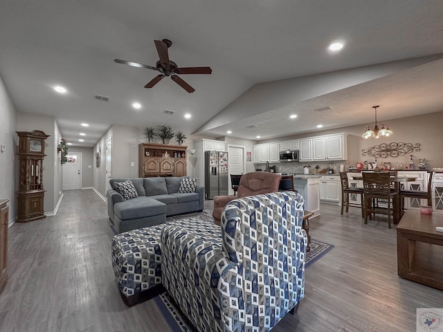 living room featuring light hardwood / wood-style flooring, ceiling fan with notable chandelier, and vaulted ceiling