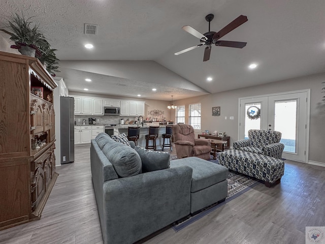 living room with sink, vaulted ceiling, french doors, and light wood-type flooring