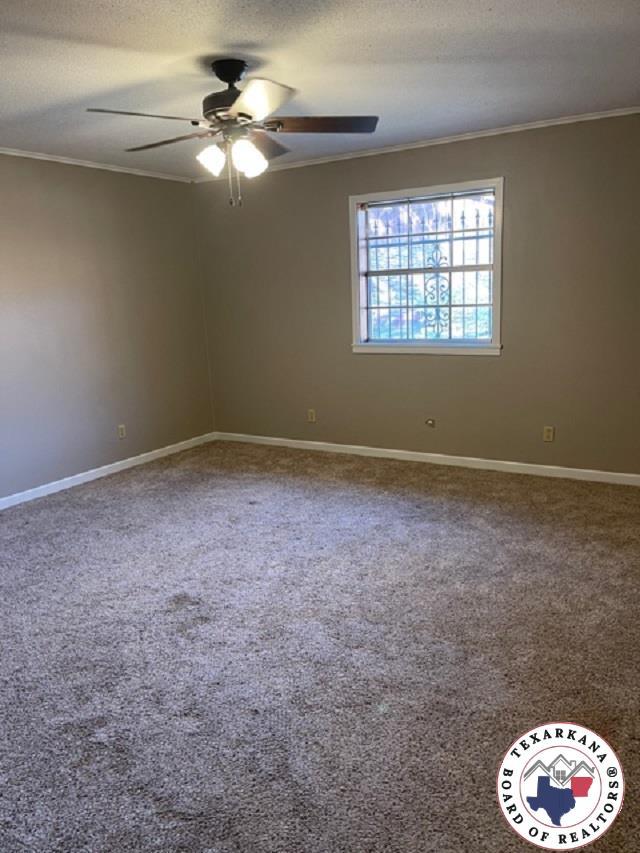 500 Wade Ln, Texarkana, TX 75501 - carpeted empty room featuring ornamental molding, a ceiling fan, baseboards, and a textured ceiling