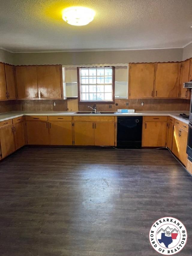 500 Wade Ln, Texarkana, TX 75501 - kitchen featuring dishwasher, a sink, light countertops, a textured ceiling, and dark wood finished floors