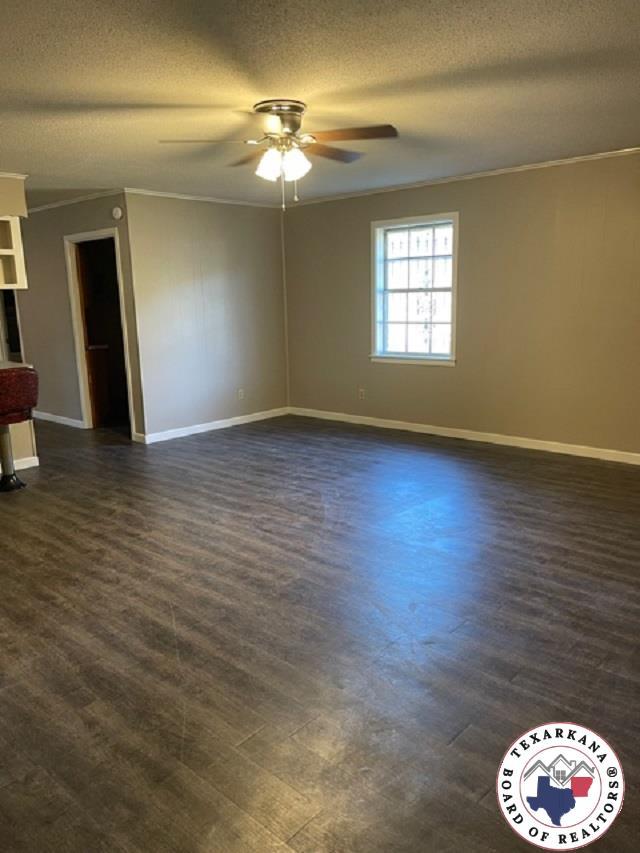500 Wade Ln, Texarkana, TX 75501 - spare room featuring ceiling fan, ornamental molding, dark wood-type flooring, a textured ceiling, and baseboards
