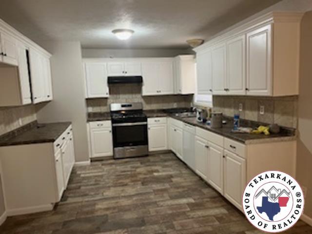 2311 Shady Ln, Texarkana, TX 75503 - kitchen with stainless steel stove, extractor fan, backsplash, dark countertops, and dishwasher