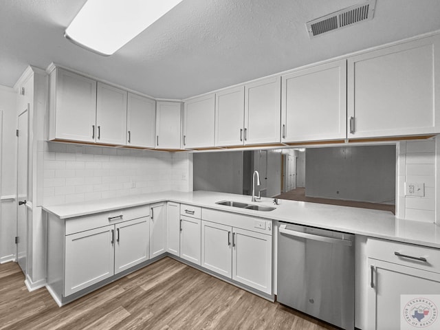 kitchen featuring a textured ceiling, white cabinets, dishwasher, sink, and light wood-type flooring