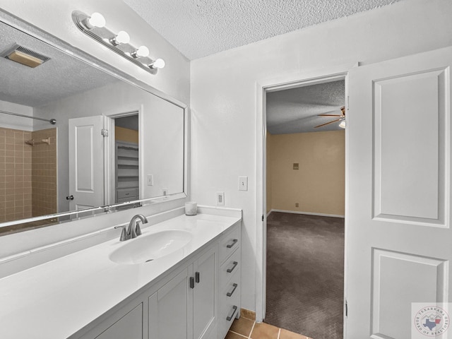 bathroom with a textured ceiling, a shower, tile patterned flooring, vanity, and ceiling fan