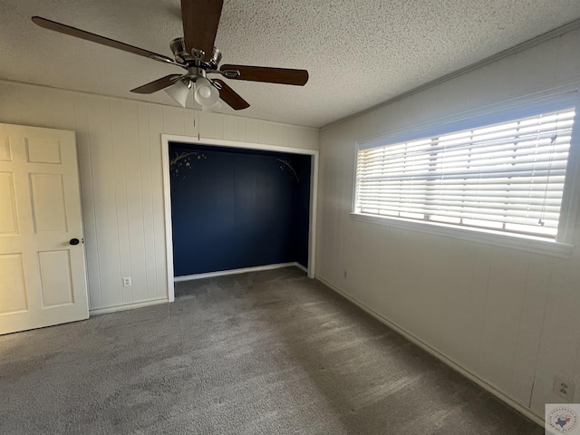 unfurnished bedroom with a closet, a textured ceiling, ceiling fan, and carpet floors