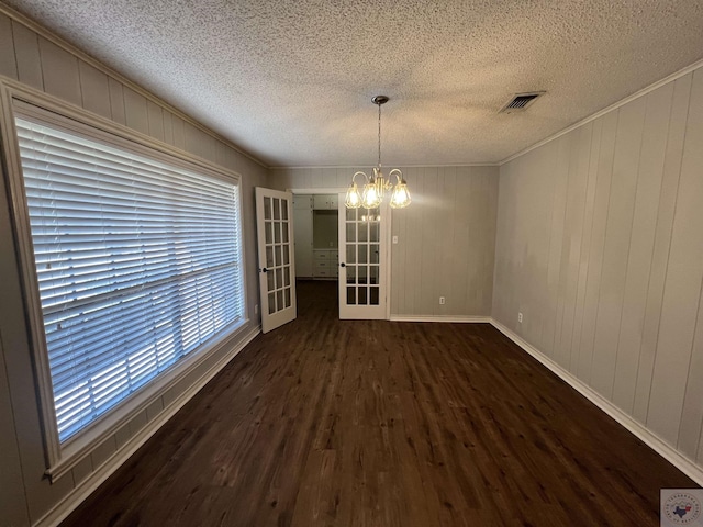 unfurnished dining area featuring visible vents, an inviting chandelier, ornamental molding, and dark wood-style flooring