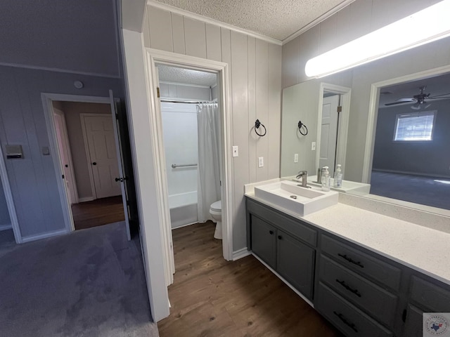 bathroom with toilet, vanity, ornamental molding, wood finished floors, and a textured ceiling