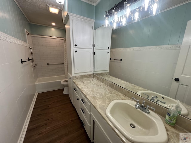 bathroom featuring vanity, wood finished floors, a textured ceiling, toilet, and shower / bathtub combination