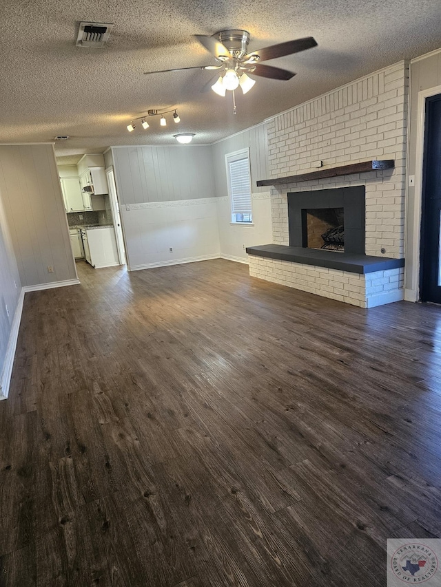 unfurnished living room with dark wood-type flooring, a brick fireplace, visible vents, and a textured ceiling