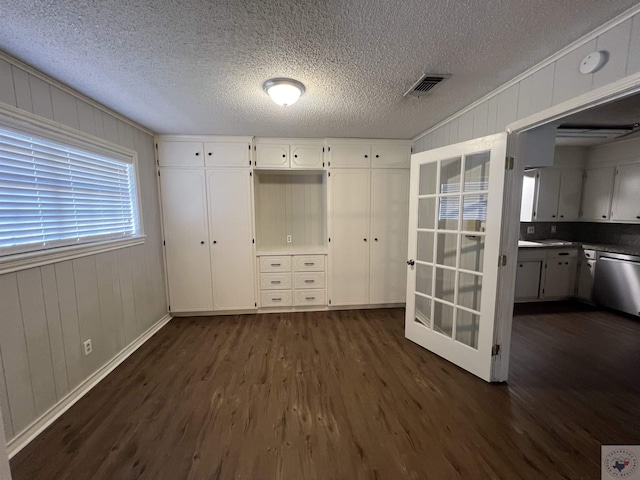 unfurnished bedroom featuring dark wood-type flooring, visible vents, and a textured ceiling