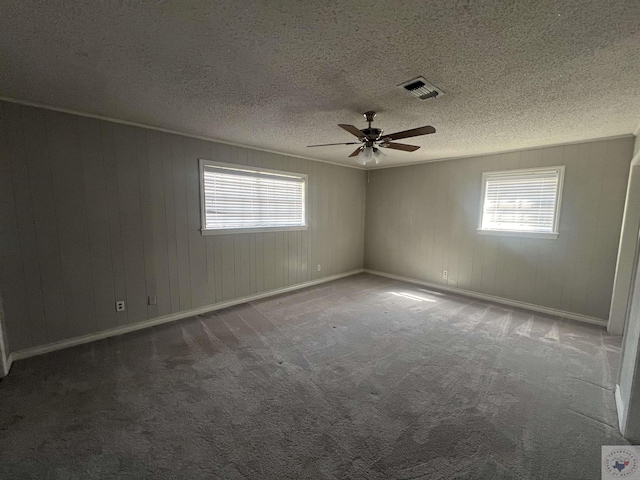 carpeted empty room with crown molding, baseboards, visible vents, and a textured ceiling