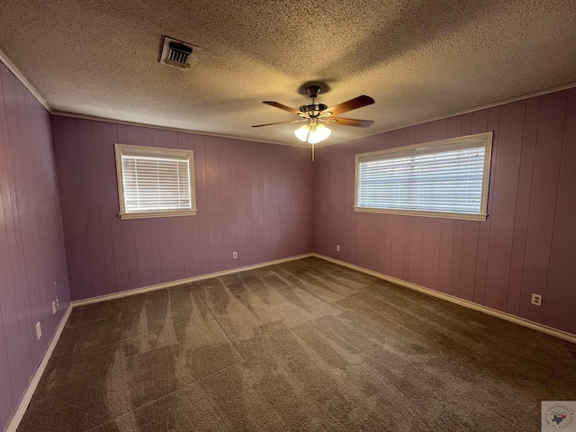 carpeted spare room with visible vents, a textured ceiling, crown molding, and ceiling fan