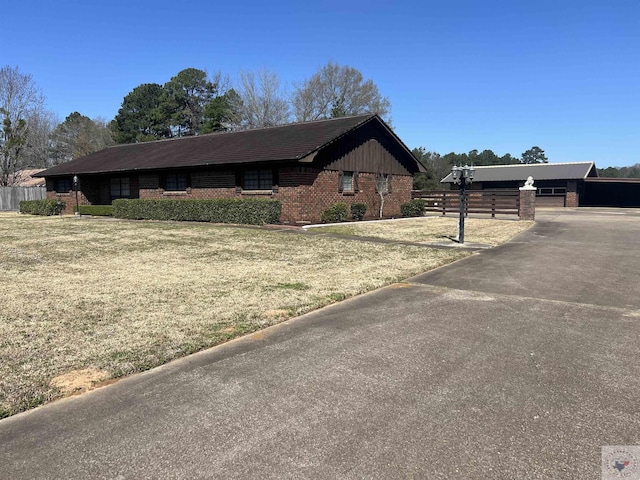 view of front of property featuring a front yard, fence, and brick siding