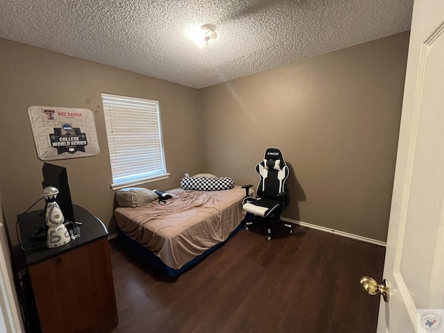 bedroom with dark wood-style floors, a textured ceiling, and baseboards