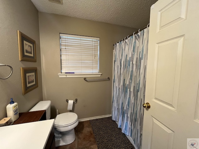 bathroom featuring toilet, tile patterned floors, a textured ceiling, and vanity