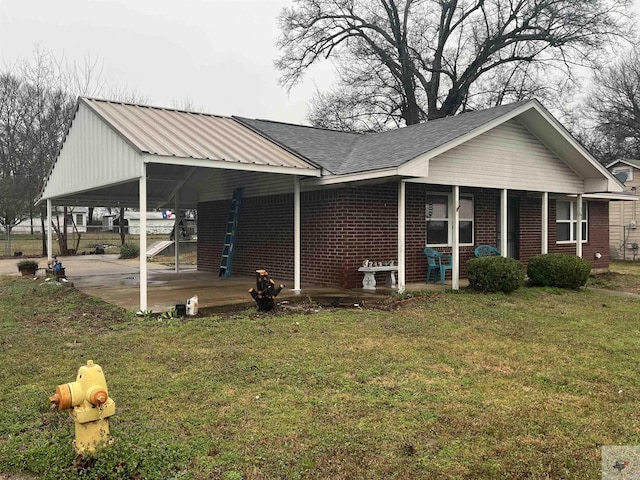 view of front of house with an attached carport, brick siding, and a front lawn