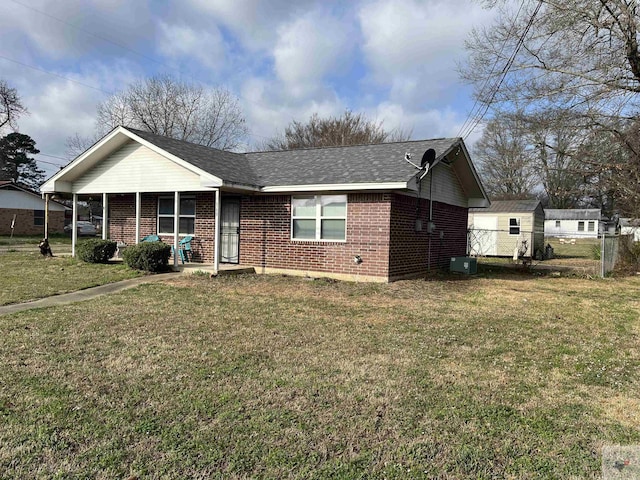 ranch-style house with a shingled roof, a front yard, brick siding, and fence