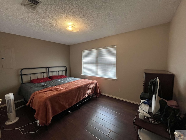 bedroom with a textured ceiling, dark wood-style flooring, visible vents, and baseboards