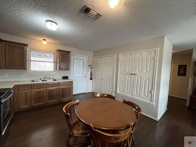 dining area with dark wood-style floors, visible vents, and a textured ceiling