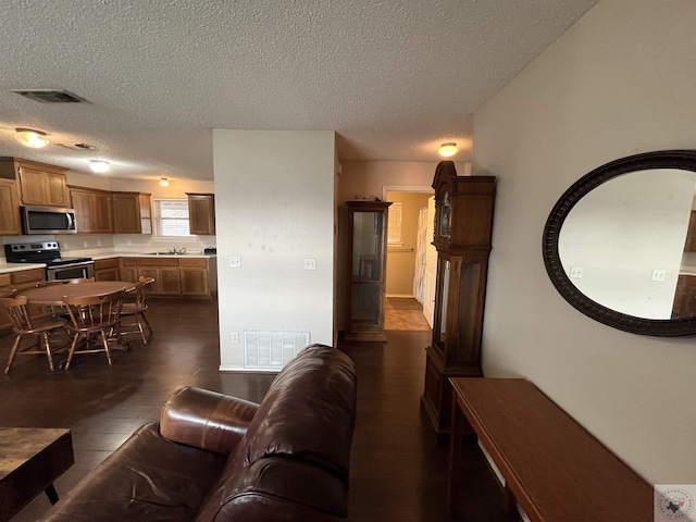 living area with a textured ceiling, dark wood finished floors, and visible vents