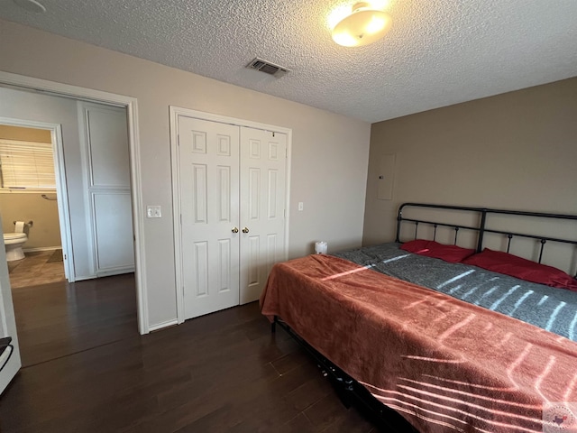 bedroom featuring baseboards, visible vents, dark wood-style floors, a textured ceiling, and a closet