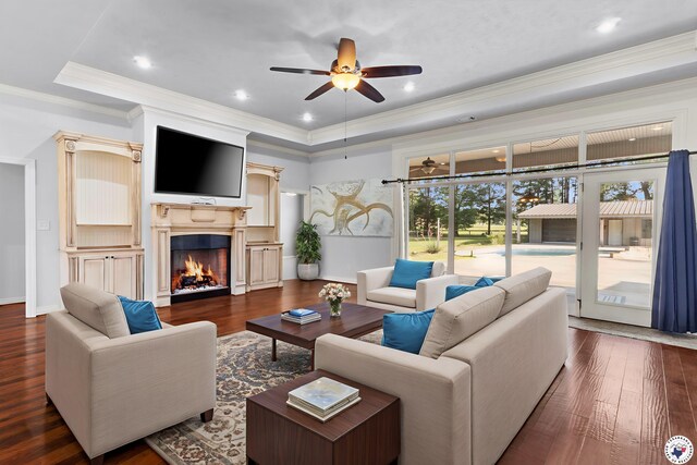 588 B K Pickering Dr, Texarkana, TX 75501 - living room featuring a tray ceiling, a ceiling fan, wood finished floors, ornamental molding, and a warm lit fireplace