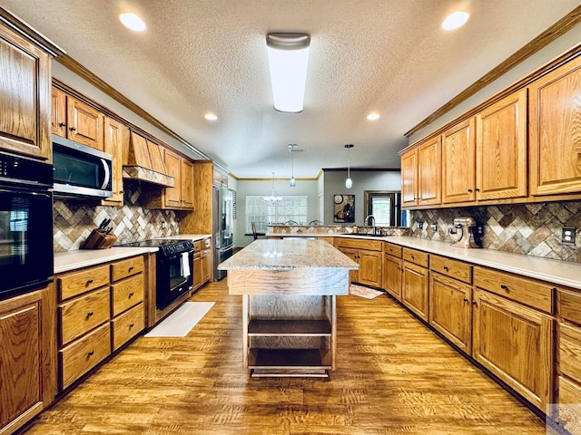 kitchen featuring pendant lighting, black appliances, a center island, backsplash, and kitchen peninsula