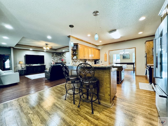 kitchen with wood-type flooring, a kitchen breakfast bar, tasteful backsplash, a textured ceiling, and dark stone countertops