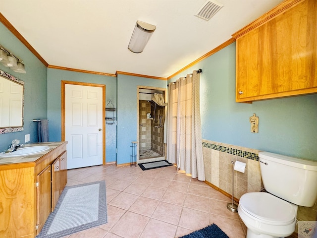 bathroom featuring tile patterned floors, vanity, toilet, ornamental molding, and tiled shower