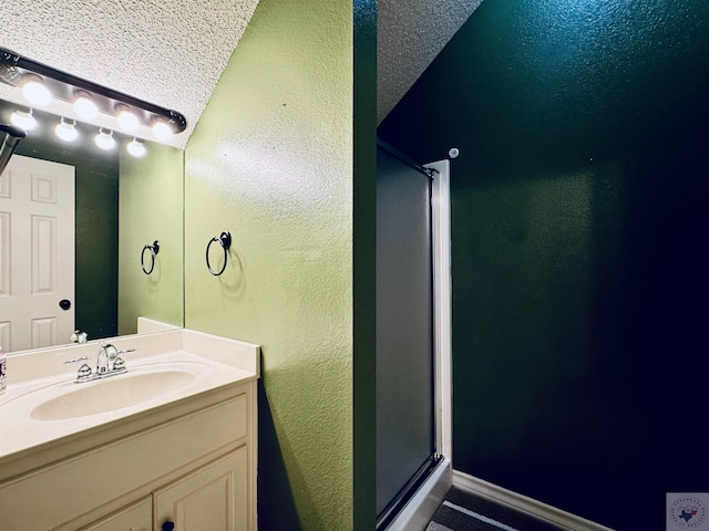 bathroom featuring vanity, a shower with shower door, and a textured ceiling