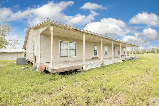 back of property with cooling unit, a porch, and a lawn