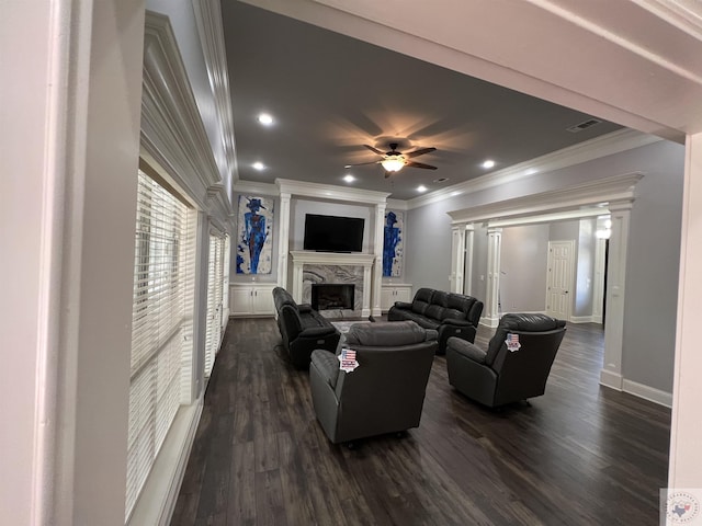 living room featuring ceiling fan, dark wood-type flooring, ornamental molding, and a fireplace