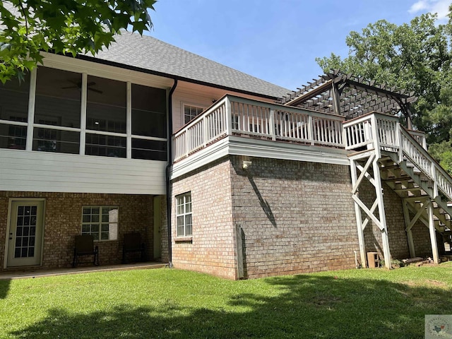 rear view of property with a sunroom, a lawn, and ceiling fan