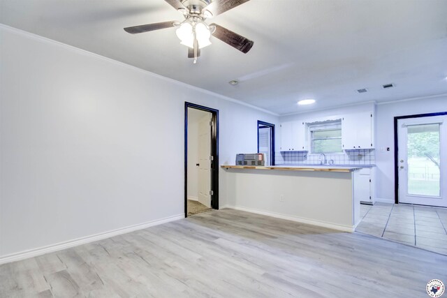 417 Carroll Ave, Wake Village, TX 75501 - unfurnished living room featuring a wood stove, ceiling fan, crown molding, and light wood-style floors