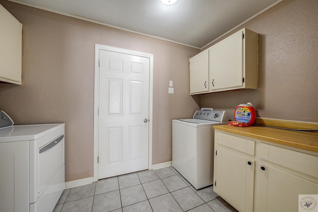 laundry room with light tile patterned floors, cabinet space, baseboards, and separate washer and dryer