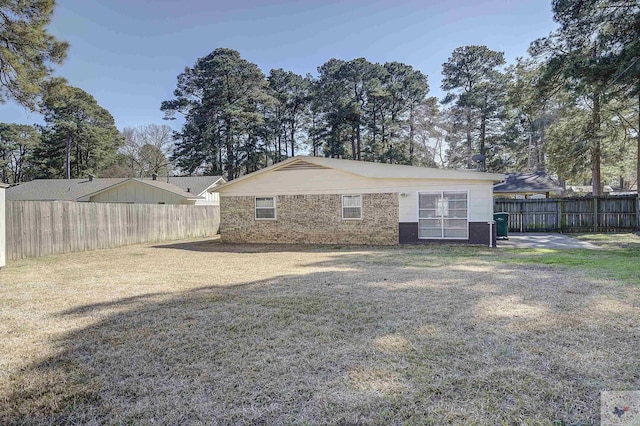 rear view of property featuring a yard, a fenced backyard, and brick siding