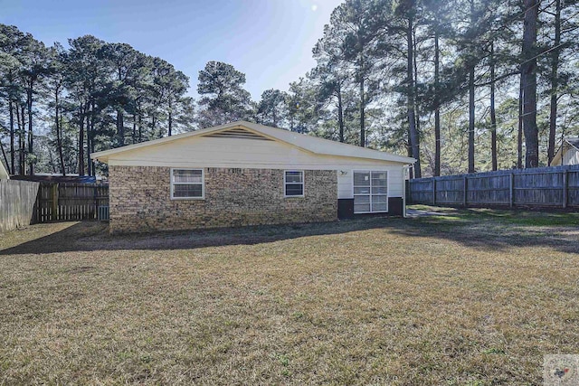 view of home's exterior featuring brick siding, a lawn, and fence