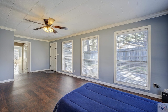 bedroom with dark wood finished floors, multiple windows, crown molding, and baseboards