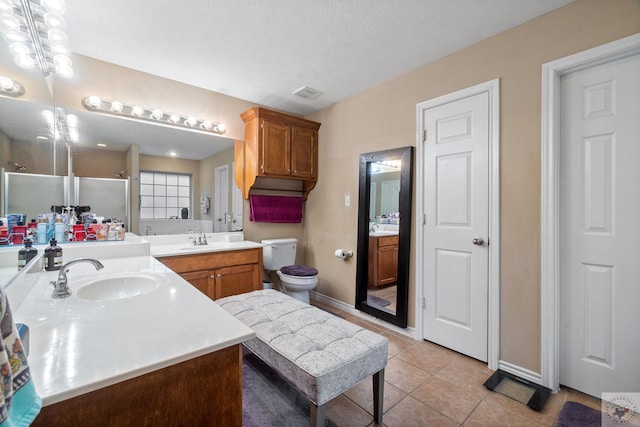 bathroom with vanity, toilet, a shower with door, and tile patterned flooring