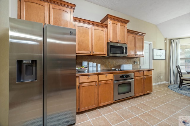 kitchen featuring light tile patterned flooring, tasteful backsplash, lofted ceiling, and appliances with stainless steel finishes