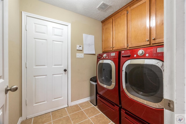 laundry area with a textured ceiling, light tile patterned floors, cabinets, and independent washer and dryer